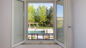 A room with a large window overlooking a swimming pool and a garden. - Borgo Ariano 8 – Apartment with pool (Volterra)