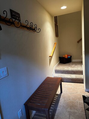 Una escalera con barandilla de madera, un banco al pie y un cartel en la pared.