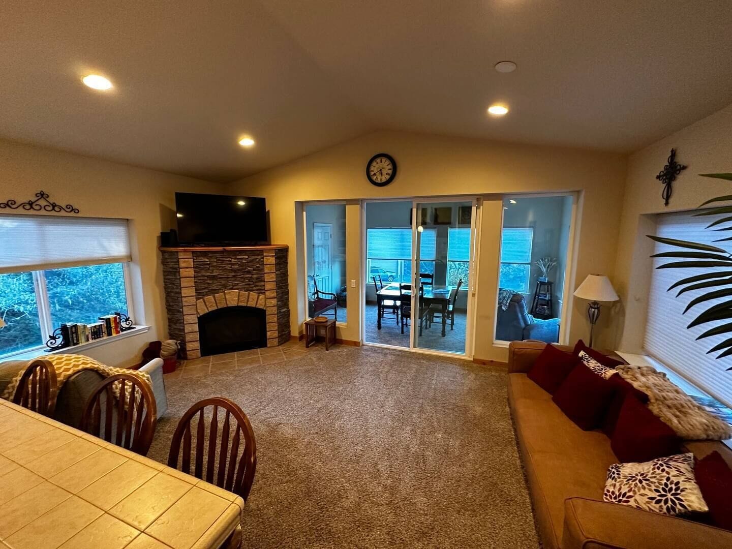 A living room with a fireplace, a dining area, and a view through glass doors to an outdoor patio.