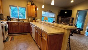 A kitchen with wooden cabinets, a large island, and pendant lighting. - Seaside Paradise at Sebastian Shores (Gold Beach)