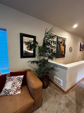 A reception area with a brown leather couch, a large potted plant, a framed mirror, and a poster on the wall.