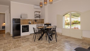 A kitchen with a dining area, a refrigerator, and a window with a view. - Borgo Ariano 18 – Apartment with pool (Volterra)