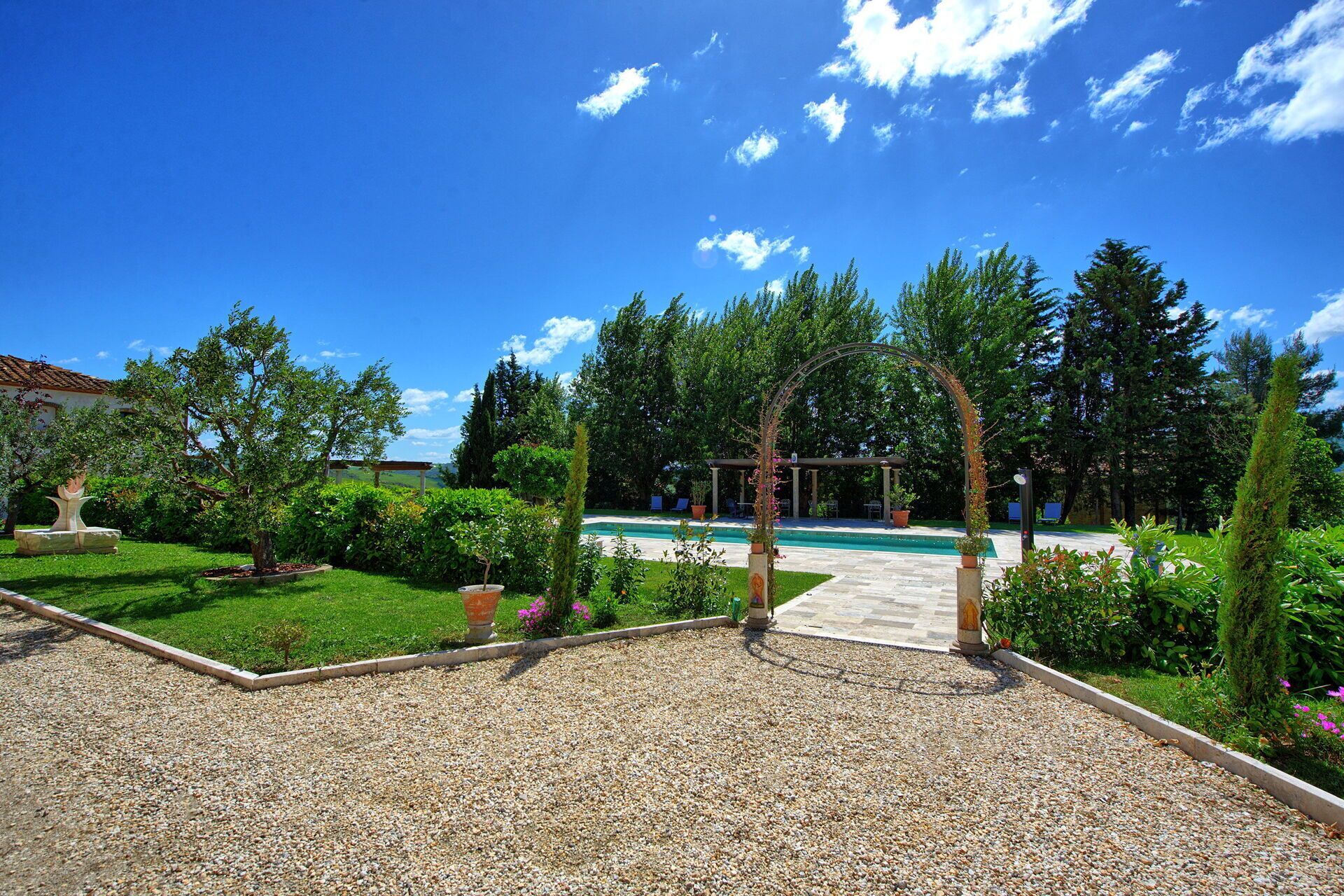 A garden with a pool, gravel paths, and various plants.