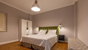 A bedroom with a bed, bedside tables, a wardrobe, and a bench. - Borgo Ariano 20 – Apartment with pool (Volterra)