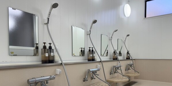 A modern bathroom with multiple sinks, mirrors, and overhead shower heads.