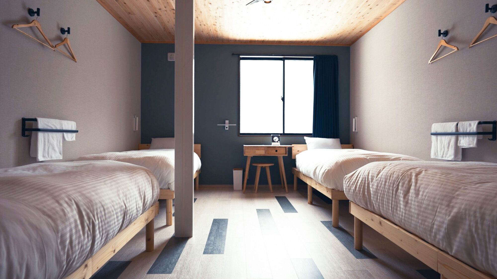 A room with two beds, a desk, and a window.