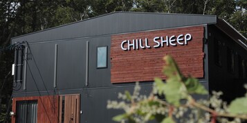 A building with a sign reading "CHILL SHEEP" on a wooden panel.