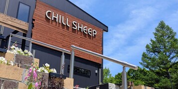 A building with a sign reading 'CHILL SHEEP' and a metal railing in front.