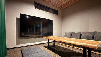 A modern living room with a flat-screen TV mounted on the wall, a wooden coffee table, and a grey sofa.
