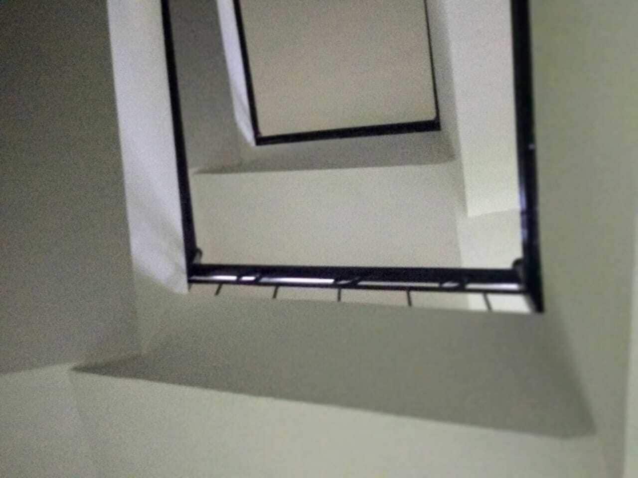 Een kamer met een witte muur en een zwarte plank.