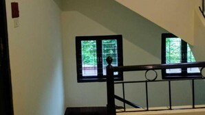 A multi-level interior with a staircase, glass railings, and windows with blinds. - Yellowbrick-Calcutta's Freshest BnB (Kolkata)