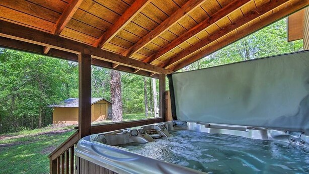 Un área de hidromasaje con terraza de madera y vistas al bosque circundante.