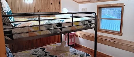 Camera con letto a castello, soffitto in legno e una finestra.