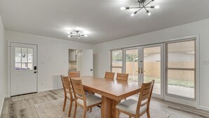 A dining area with a wooden table and chairs, a patterned rug, and a ceiling light fixture.