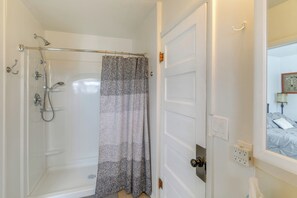 A bathroom with a shower, a door with a mirror, and a towel rack. - Farmhouse w/ Horse Corral Near Wind River Arena (Rigby)