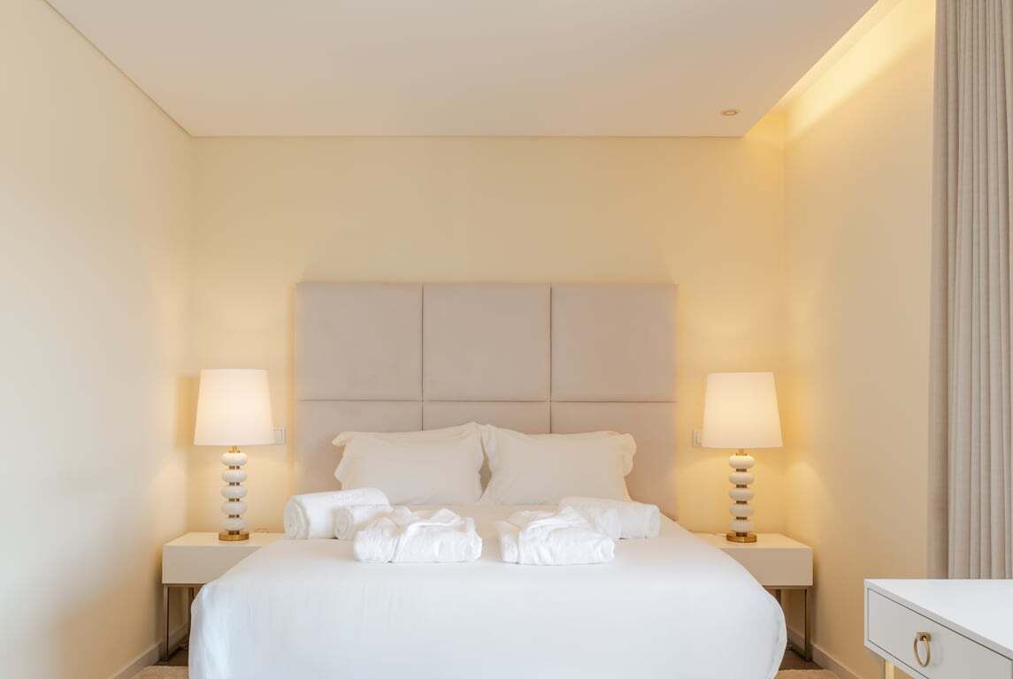 Une chambre d’hôtel avec un grand lit, deux tables de chevet et une petite table de nuit.