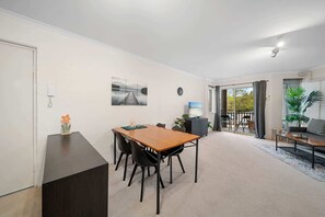Ein modernes Wohnzimmer mit Essbereich, einem Fernseher und Blick ins Freie.