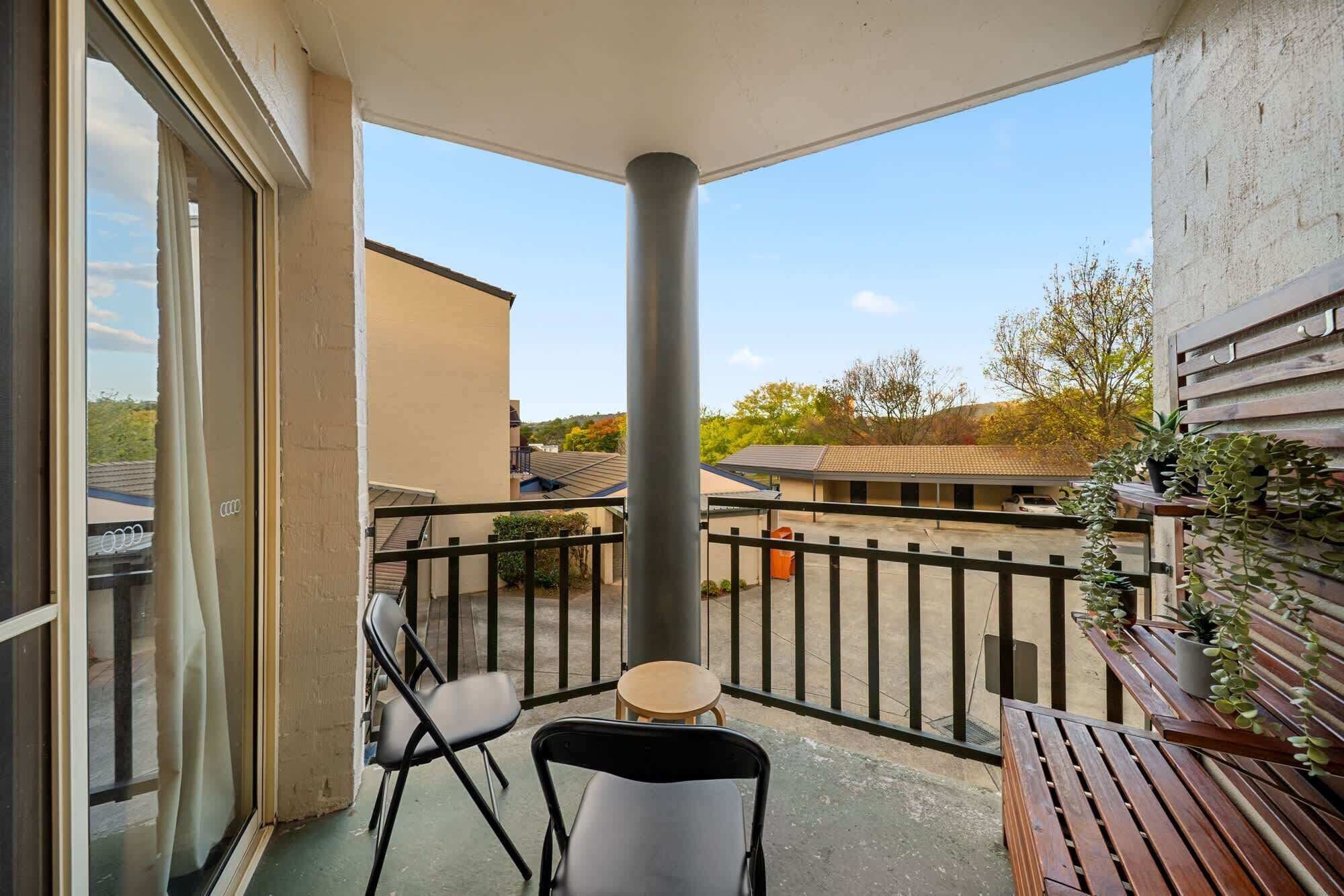 A balcony with a view of neighboring buildings and trees.