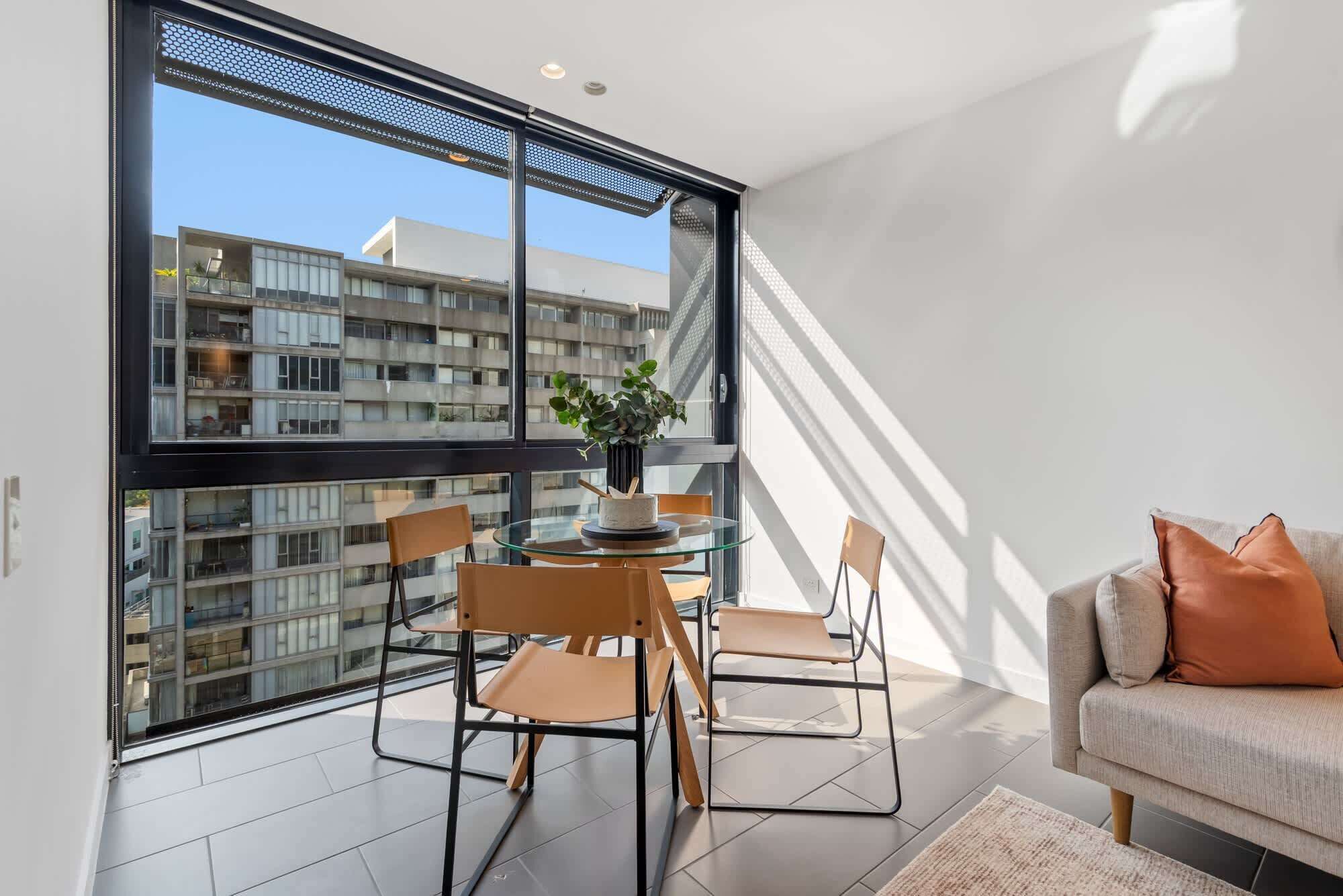 Un apartamento moderno con balcón, una mesa redonda de vidrio y un sofá.