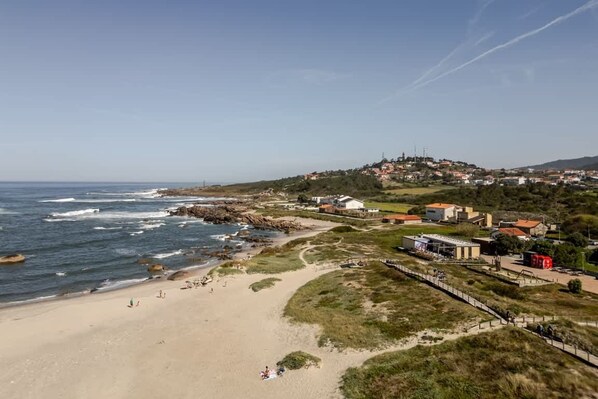 Een kustplaatsje met een strand, gebouwen en een glooiend achtergrondlandschap.