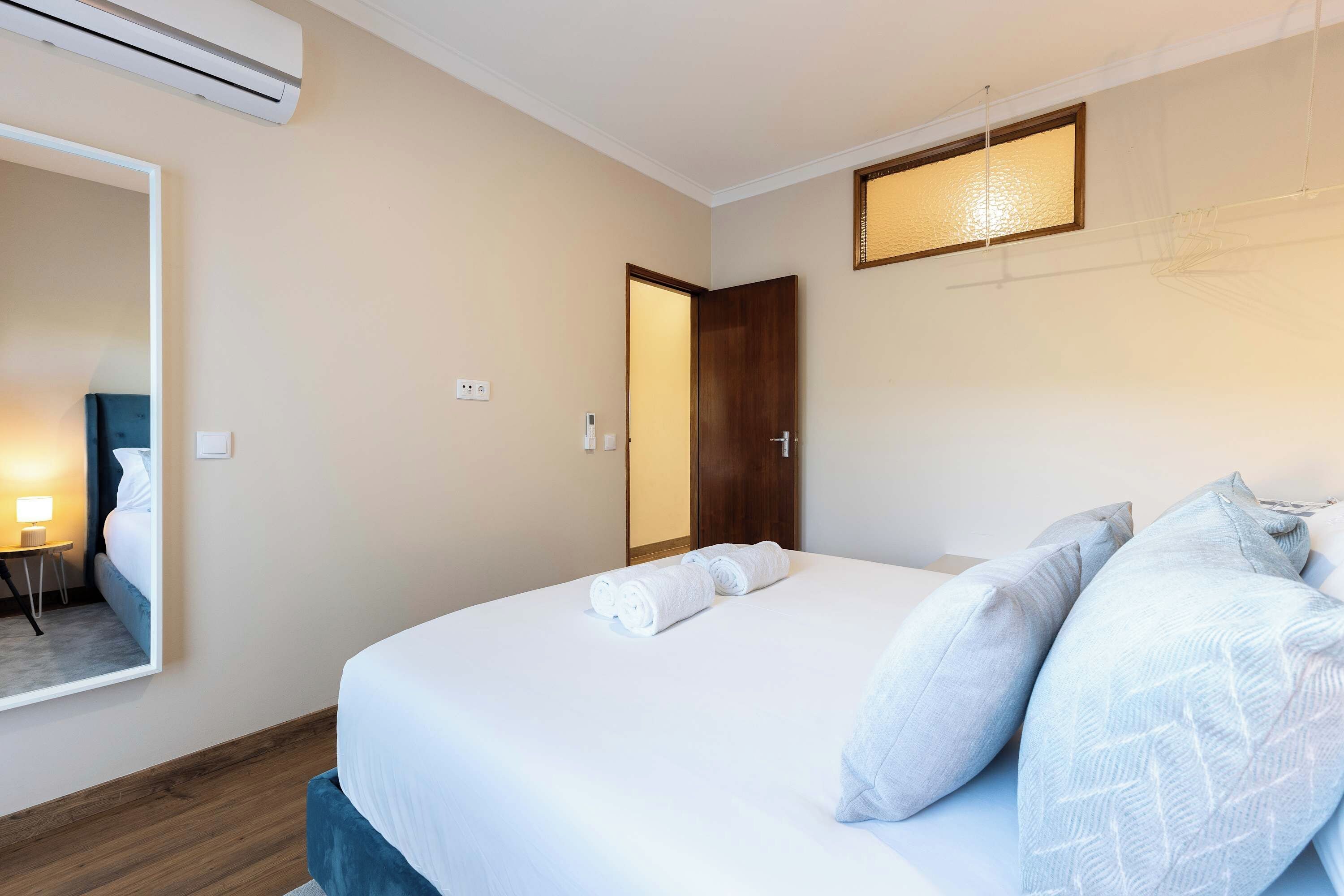 Ein Hotelzimmer mit Bett, Nachttisch, Lampe und Spiegel.