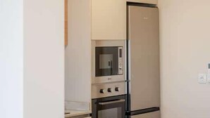 Eine kleine Küche mit integrierten Geräten, einer Holz Arbeitsplatte und weißen Schränken.