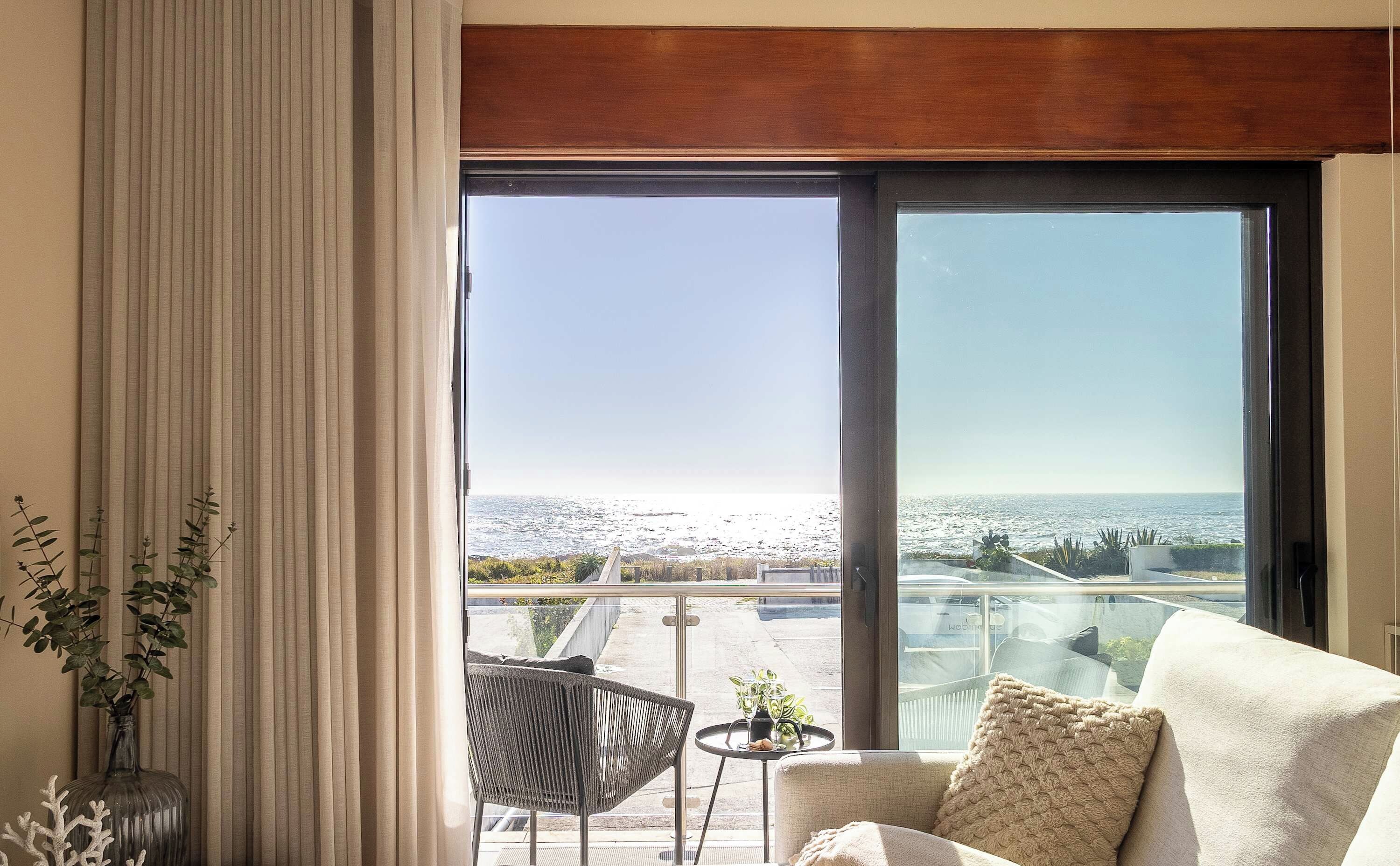 Una habitació amb una gran porta corredissa de vidre que dona a un balcó amb vista al mar.