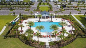 A hotel with a swimming pool, palm trees, and a parking lot. - Cozy & Stylish 2BR Condo, Prime Storey Lake Spot (Kissimmee)