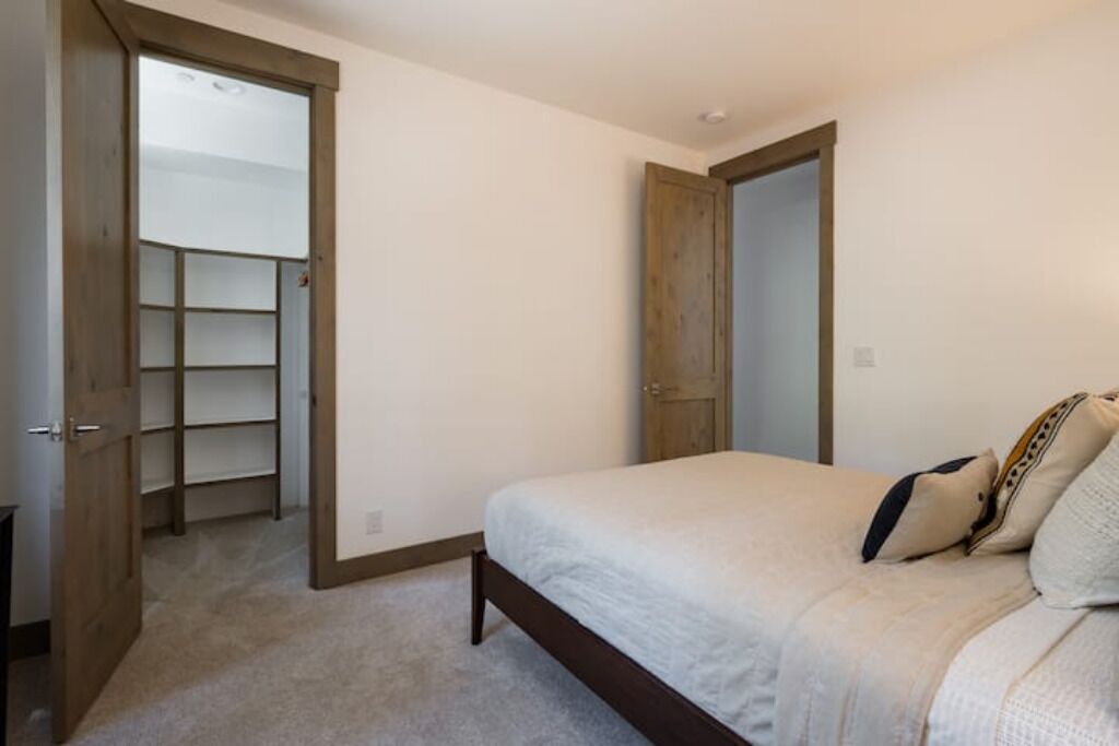 Un dormitorio con cama, una puerta de madera y un armario con estantes.