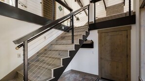 Eine Treppe mit Metallgeländer und einer Holztür am Fuß.