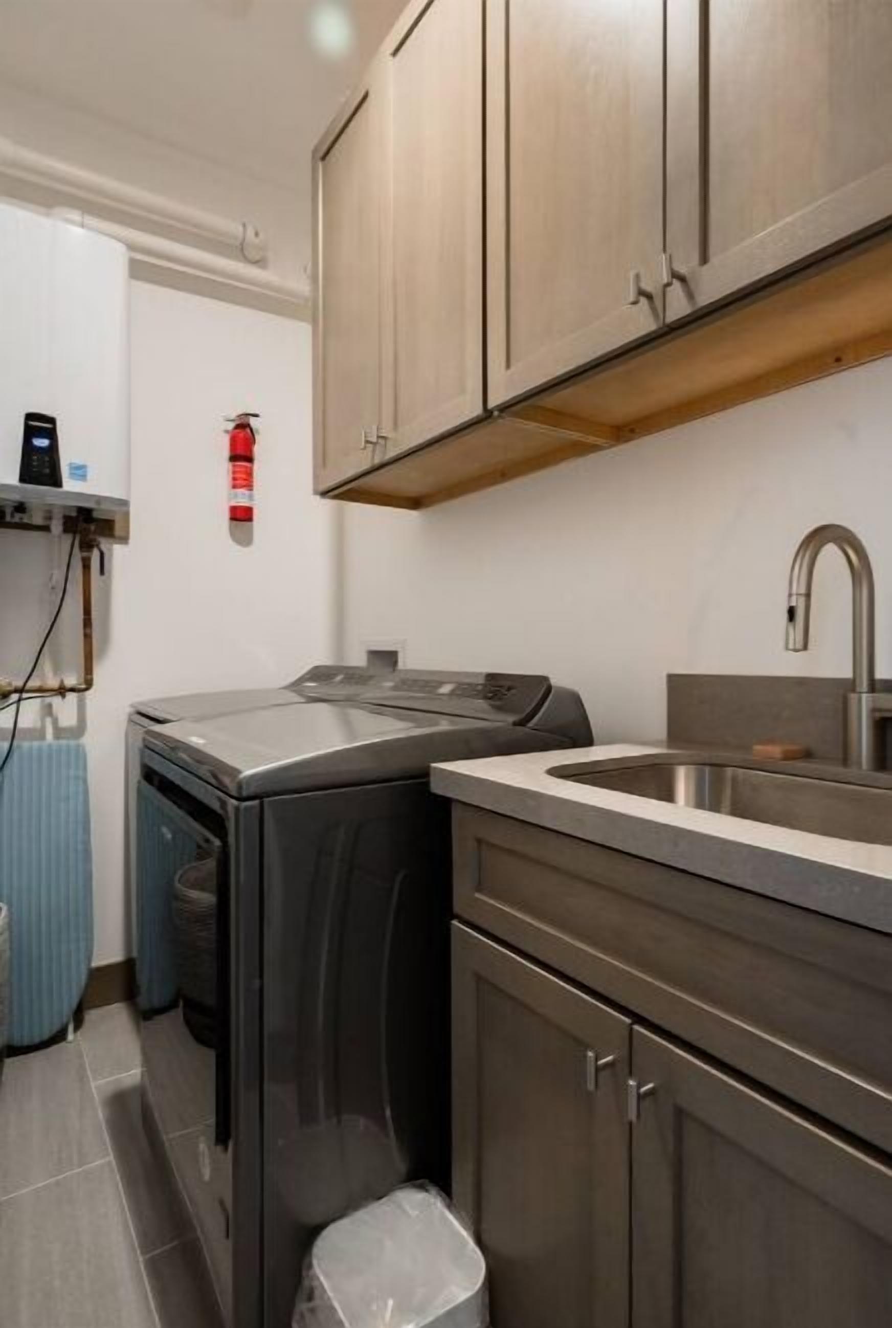 Una cocina compacta con electrodomésticos de acero inoxidable, un lavamanos integrado y armarios de madera.