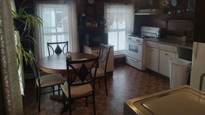 Une cuisine de taille réduite comprenant une table à manger, des chaises, une cuisinière et un évier.