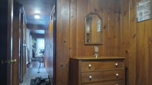 Un couloir aux murs lambrissés, avec une commode en bois et un miroir.