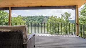 Une terrasse extérieure couverte offrant une vue sur un lac et une forêt.