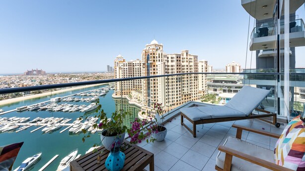 Un balcón con vista a un puerto deportivo y un gran edificio de hotel.