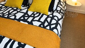 A neatly made bed with a patterned bedspread, two pillows, and a headboard. There are two framed pictures on the wall above the bed. - Pinvidik apartment with private parking close to city center and train station (Saint-Brieuc)
