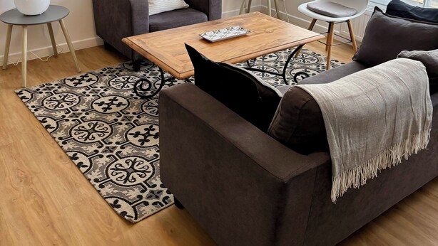 A modern living room with a sofa, a coffee table, and a chair. There is a painting on the wall and a window with a view of buildings. - Pinvidik apartment with private parking close to city center and train station (Saint-Brieuc)