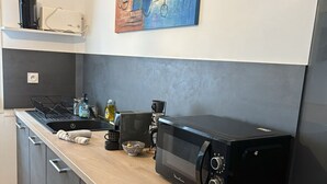 A modern kitchen with a black microwave, a coffee maker, and a kettle on the counter. - Pinvidik apartment with private parking close to city center and train station (Saint-Brieuc)