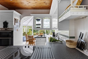 A modern kitchen with white cabinetry, a black countertop, and a wooden ceiling.