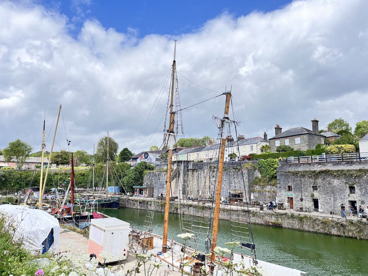A harbor with boats, a stone wall, and buildings in the background.