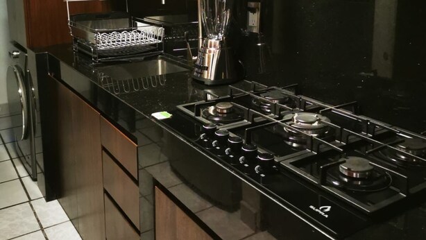 Une cuisine moderne avec un plan de travail noir, des appareils en acier inoxydable et des armoires en bois.