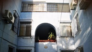Un immeuble à plusieurs étages, doté de fenêtres grillagées, d’une arche centrale et d’une enseigne indiquant le nom « Punto ».