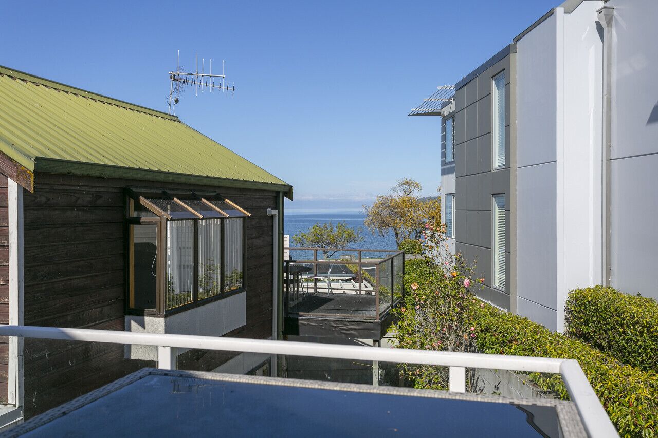 A modern building with a green roof and a balcony overlooking a body of water.