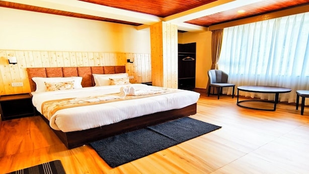 A modern hotel room with a large bed, a small round table, and a seating area. - Aurora The Mall Darjeeling (Darjeeling)
