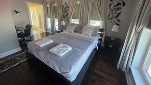 Une chambre à coucher avec un grand lit, deux tables de chevet, un bureau et une chaise.