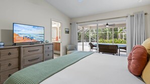 A hotel room with a bed, a TV, a desk, and a balcony with a pool.