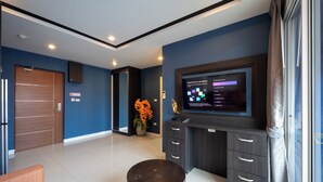Une chambre d’hôtel moderne équipée d’un téléviseur à écran plat, d’une porte en bois, d’une plante en pot et d’une table ronde.