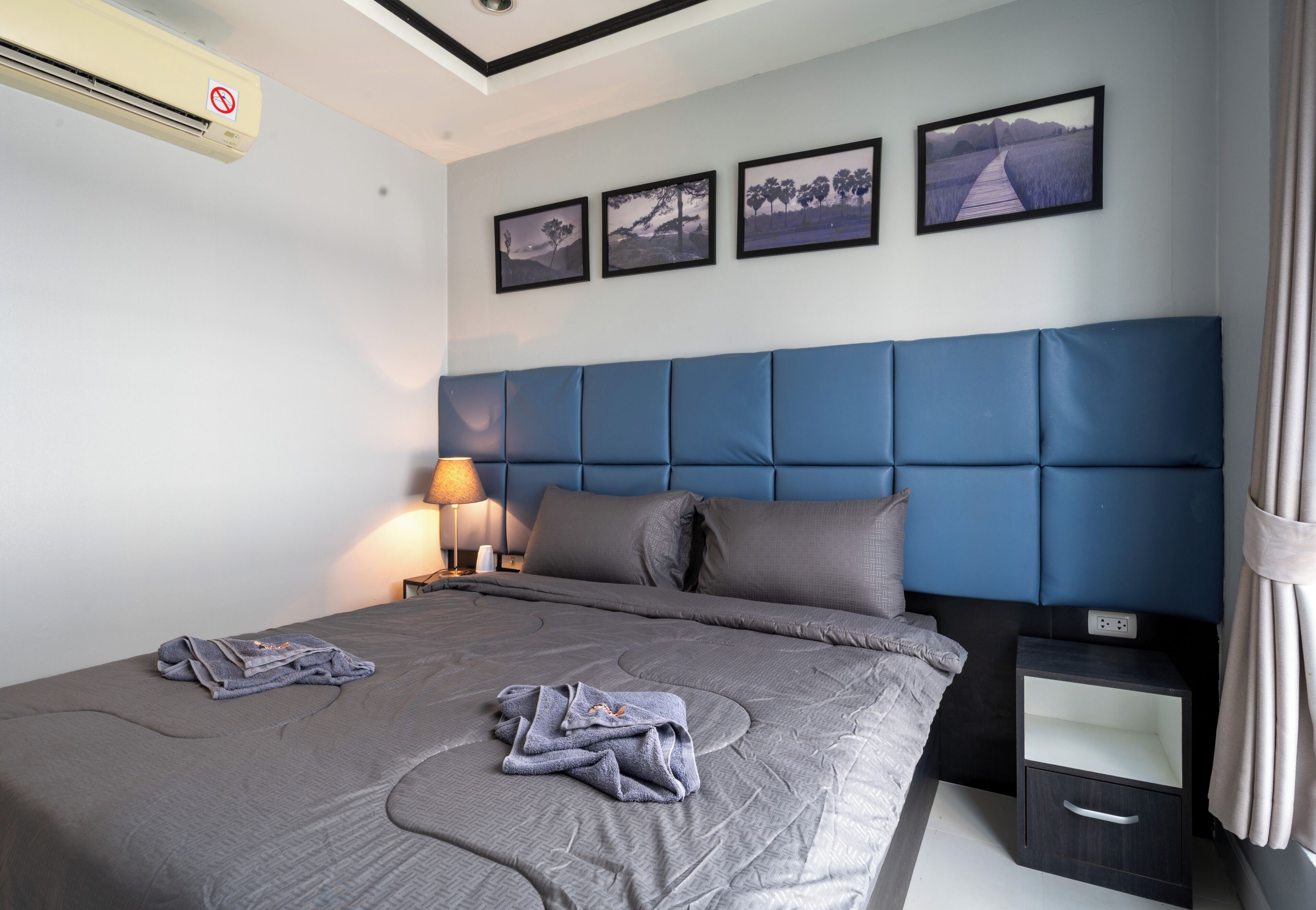 Una camera d'albergo con un letto grande, un comodino, una lampada e tre quadri appesi al muro.