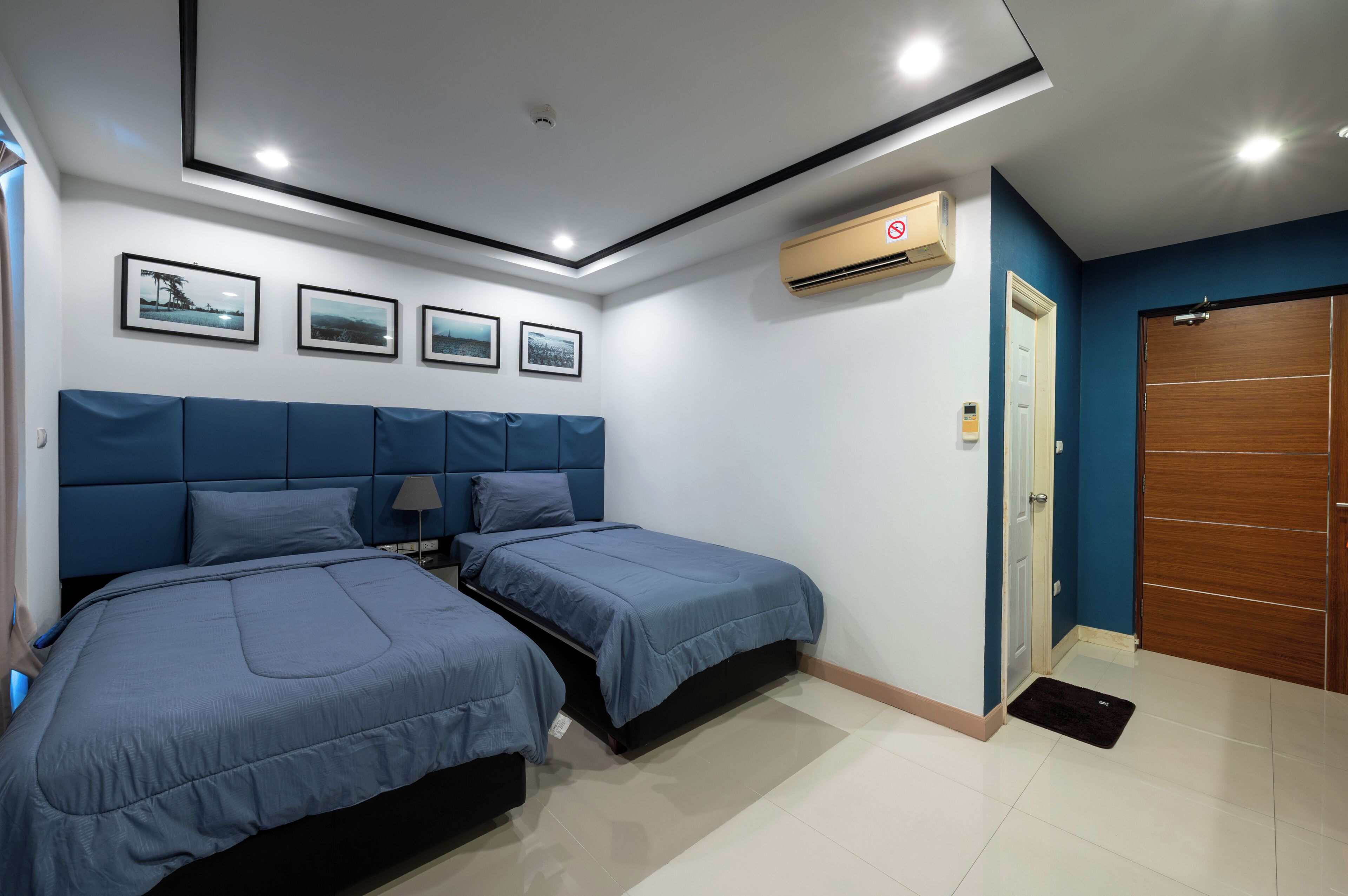A bedroom with two beds, a ceiling light, and a wall-mounted air conditioner.