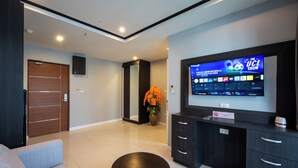 Un salon moderne avec un téléviseur à écran plat, un canapé, une table basse, un meuble et une plante en pot.